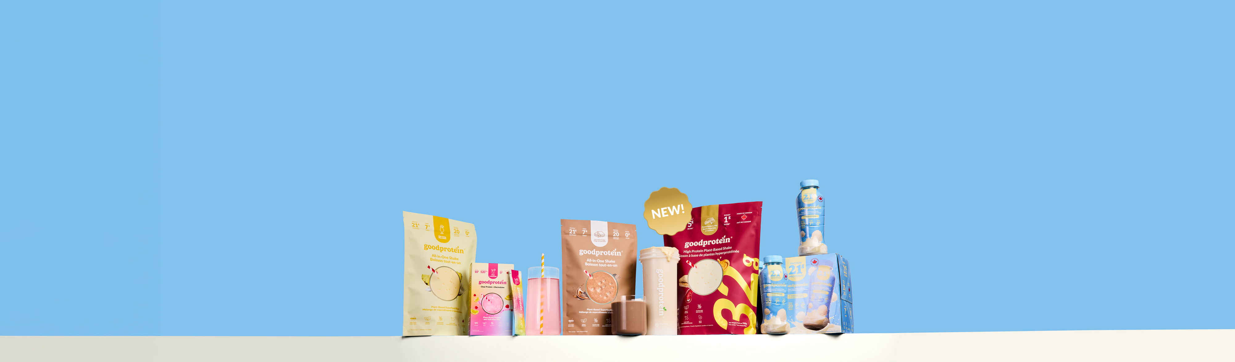 A row of assorted packaged snack and candy products arranged on a white surface against a solid light blue background. Visible brands include Goldbunnies, Snickersaas, and Snickersaas Kids.